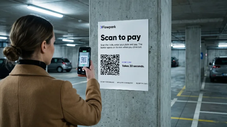 A driver scans the QR code on a Flowpark lot sign, phone in hand